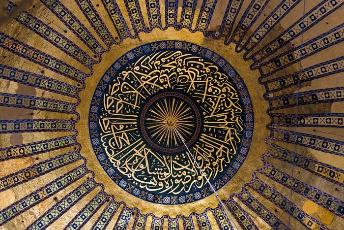Ornate Ottoman calligraphic roundel on the ceiling of Hagia Sophia featuring Quranic inscriptions surrounded by intricate geometric tilework, Istanbul