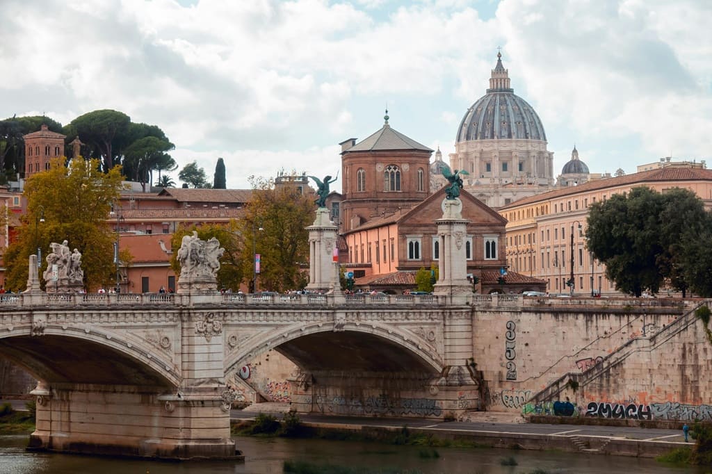 Vue sur le Tibre et le pont Victor-Emmanuel II, avec le dôme de la basilique Saint-Pierre dominant les toits de Rome : le panorama classique de la Ville Éternelle