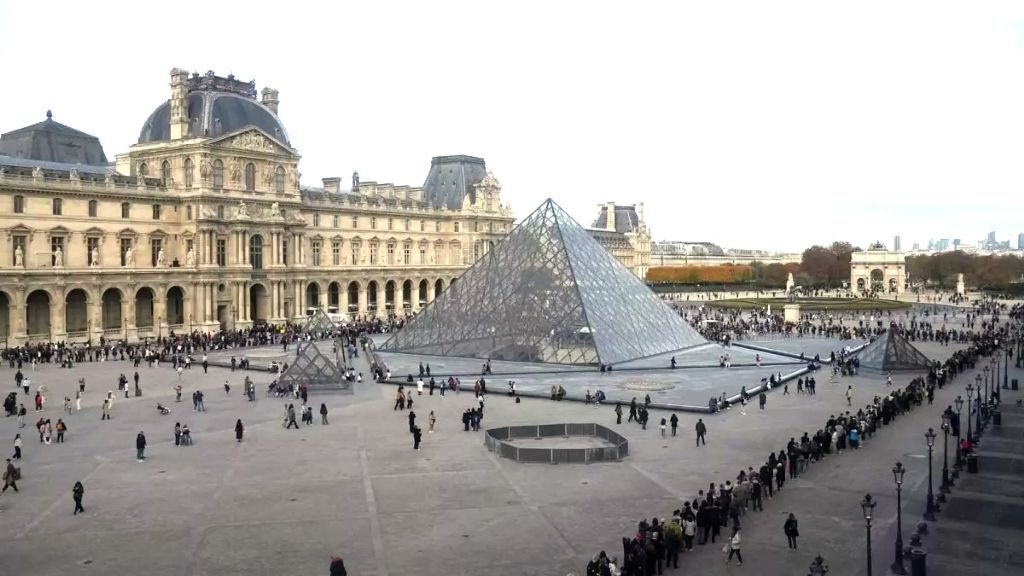 A long ticket queue of visitors waiting outside the Louvre's glass pyramid in Paris