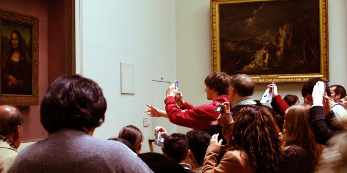 Visitors photographing the Mona Lisa in the Denon Wing of the Louvre