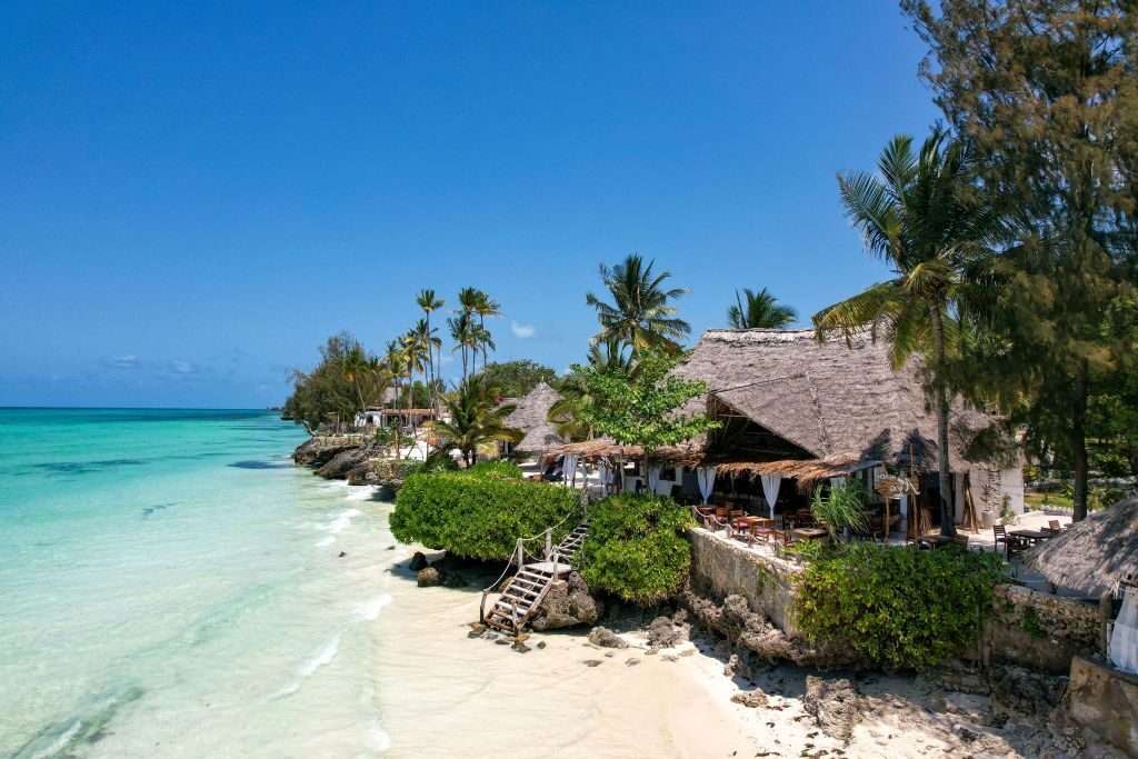 Zanzibar east coast with thatched-roof beach restaurants, turquoise water, and palm trees