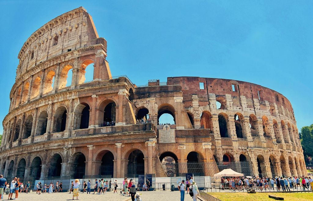 Die Außenfassade des Kolosseums in Rom, Italien, mit Besuchern am Eingang, die Tickets kaufen.