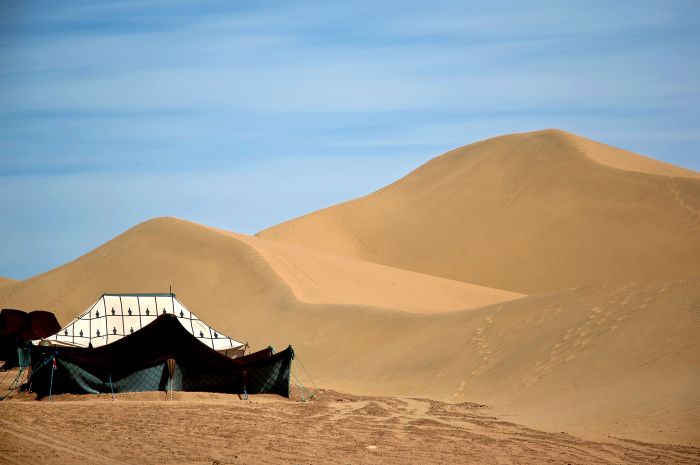 Rolling stone desert of the Agafay near Marrakech with a tented camp and the High Atlas mountains