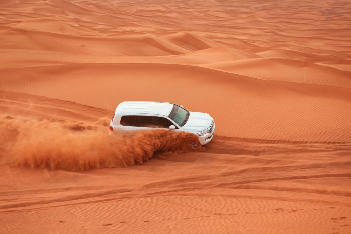 Private desert safari tour from Dubai with a 4x4 vehicle on the red dunes at sunset