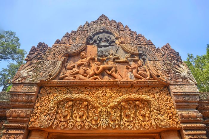 Deeply carved pink sandstone lintel and pediment at Banteay Srei temple near Siem Reap