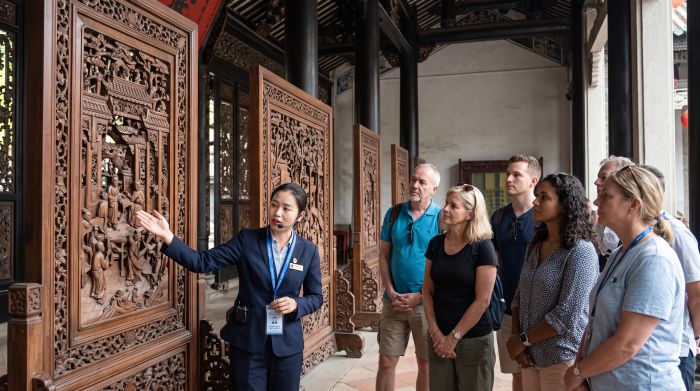 Licensed guide explaining the carved screens of the Chen Clan Ancestral Hall to a small group in Guangzhou