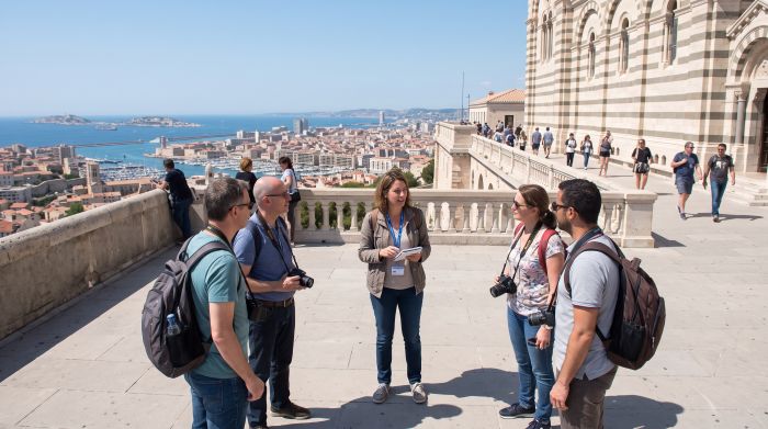 Guide conférencier et visiteurs sur le parvis de Notre-Dame de la Garde au-dessus de Marseille